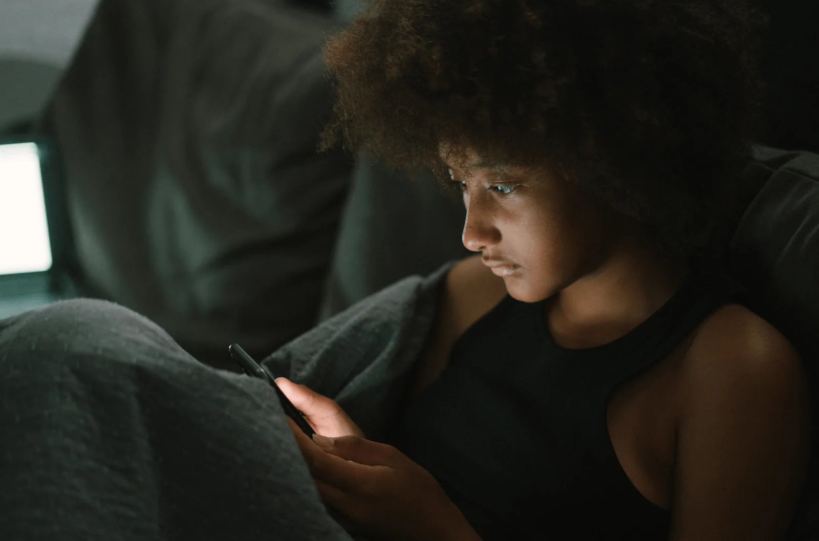 Child looking at a tablet in a dimly lit room.