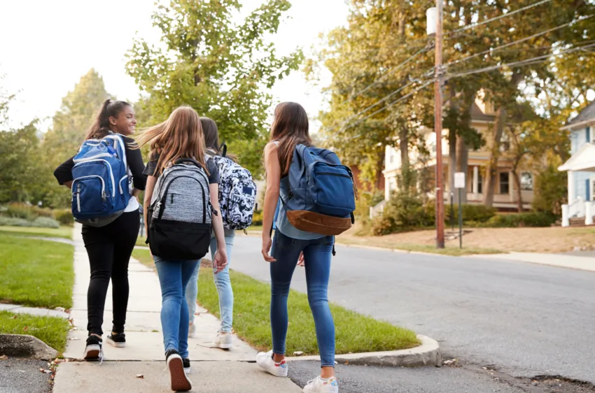 Children with backpacks walking towards school.